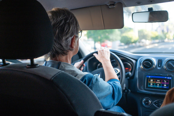 Back view of mature woman driving car in the city Transport people concept and safety drive Modern car with radio and navigator device | Pension de reversion permis de conduire