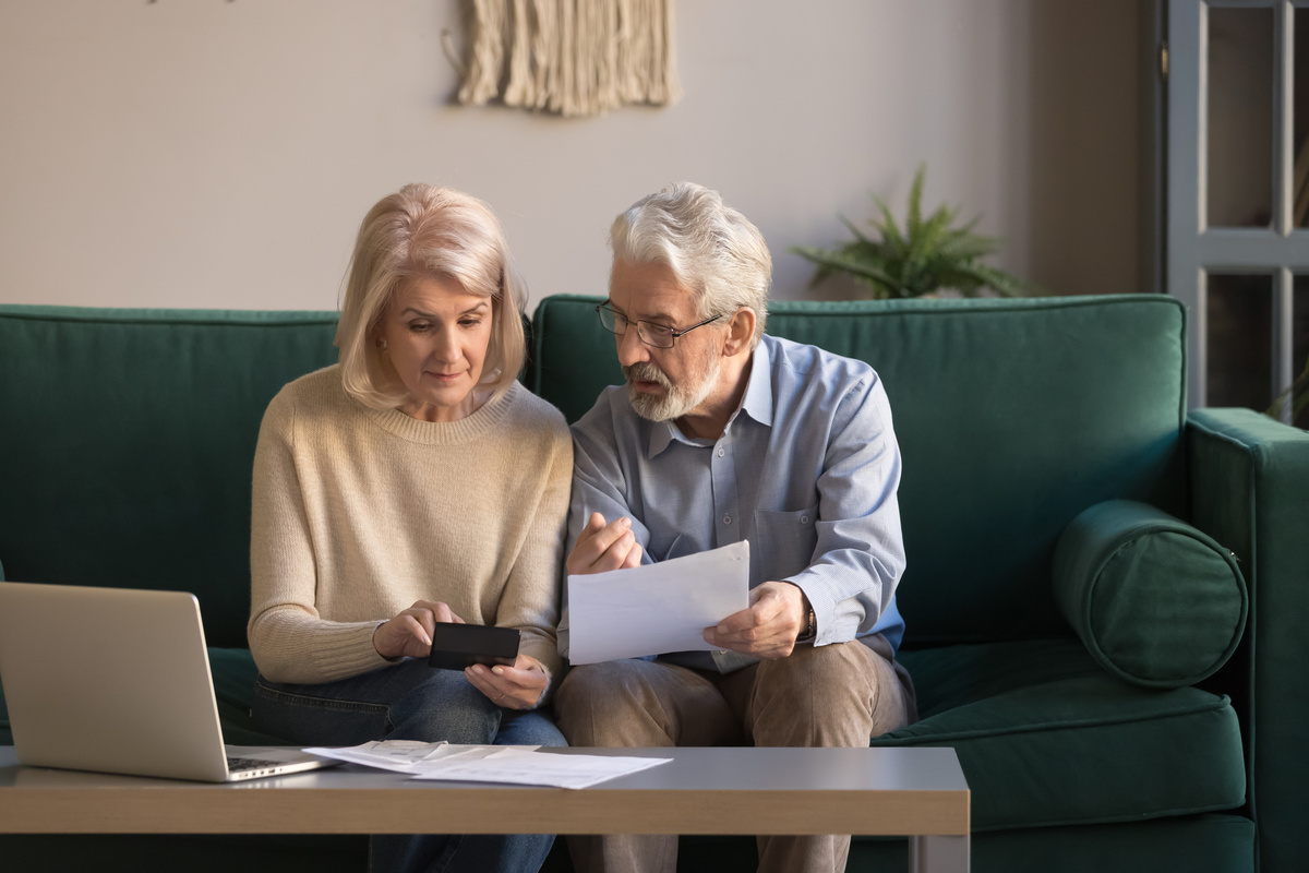 Serious mature couple calculating bills checking domestic finances | Pension de reversion pension versée en retard en novembre
