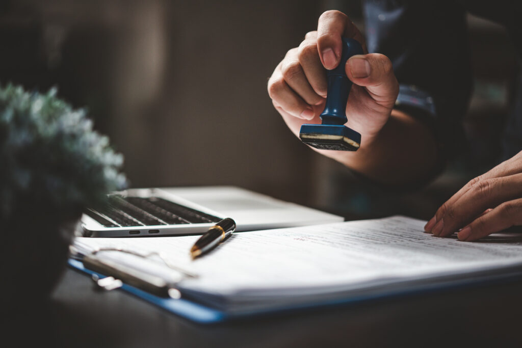 Man stamping approval of work finance banking or investment marketing documents on desk | Pension de reversion renoncer à un héritage