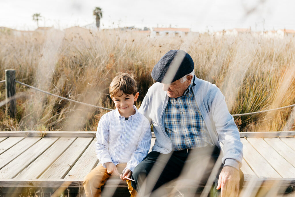 Grandfather sitting with his grandson on boardwalk relaxing | Pension de reversion épargne pour petits-enfants