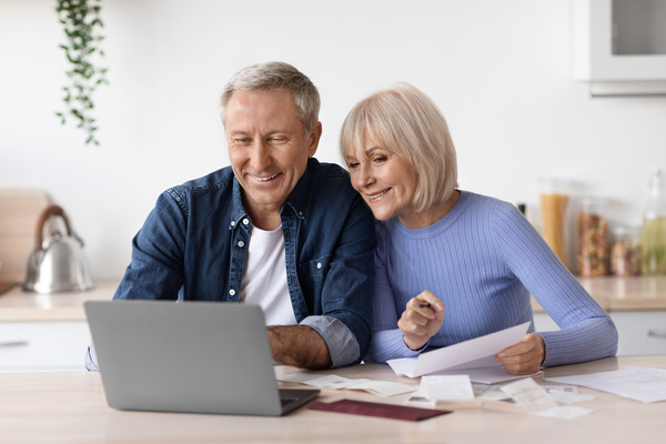 Happy pensioners sittting in front of computer reading emails | Pension de reversion revalorisation retraite complémentaire