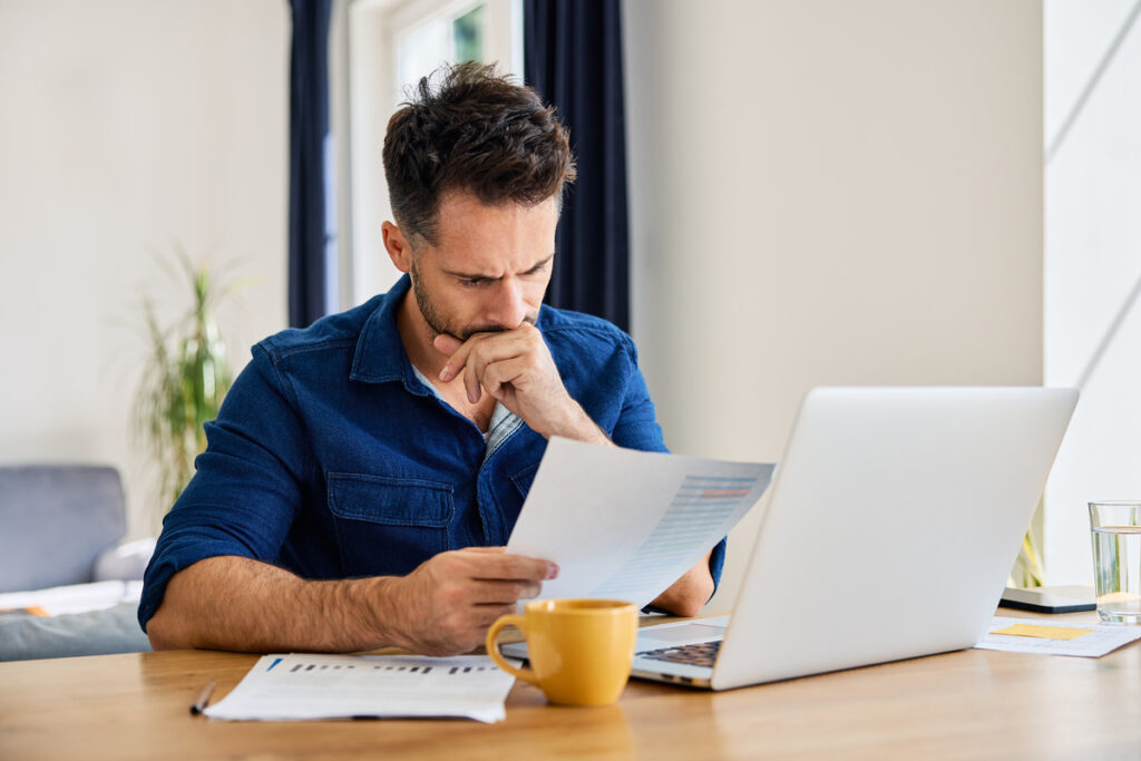 Sad man looking at financial documents at home | Pension de reversion calculer sa retraite