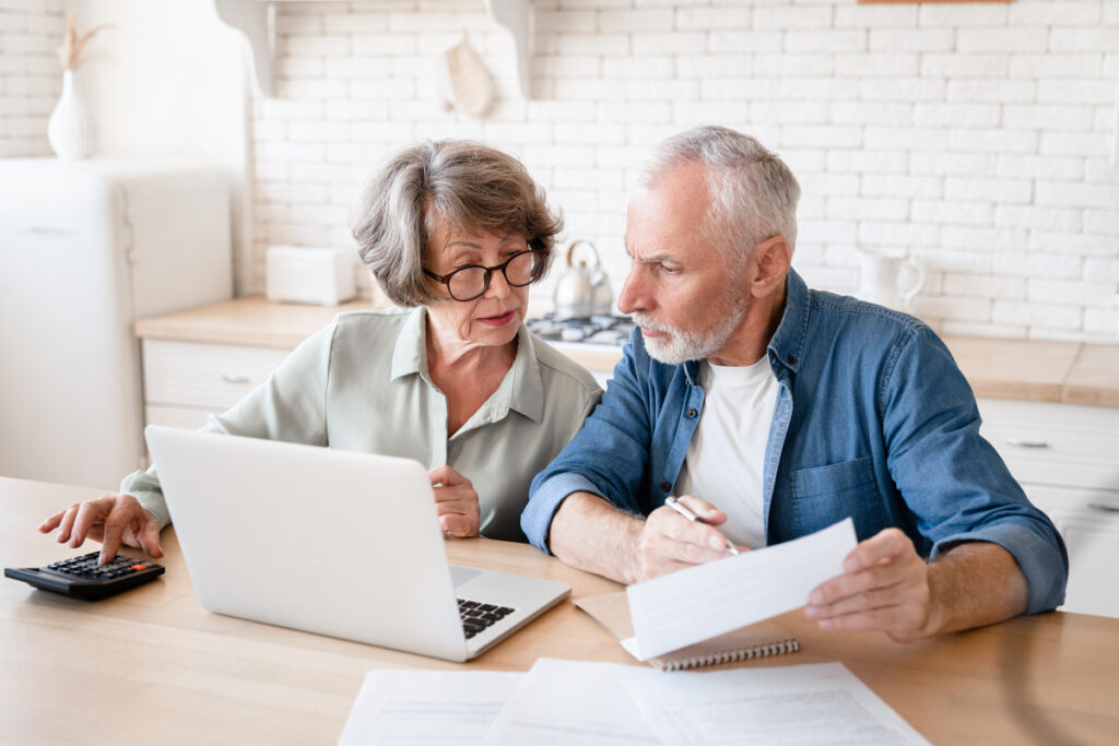 Busy caucasian old elderly senior couple making calculations at home kitchen checking the document revising data information counting domestic bills and rentals | Pension de reversion avis imposition CARSAT