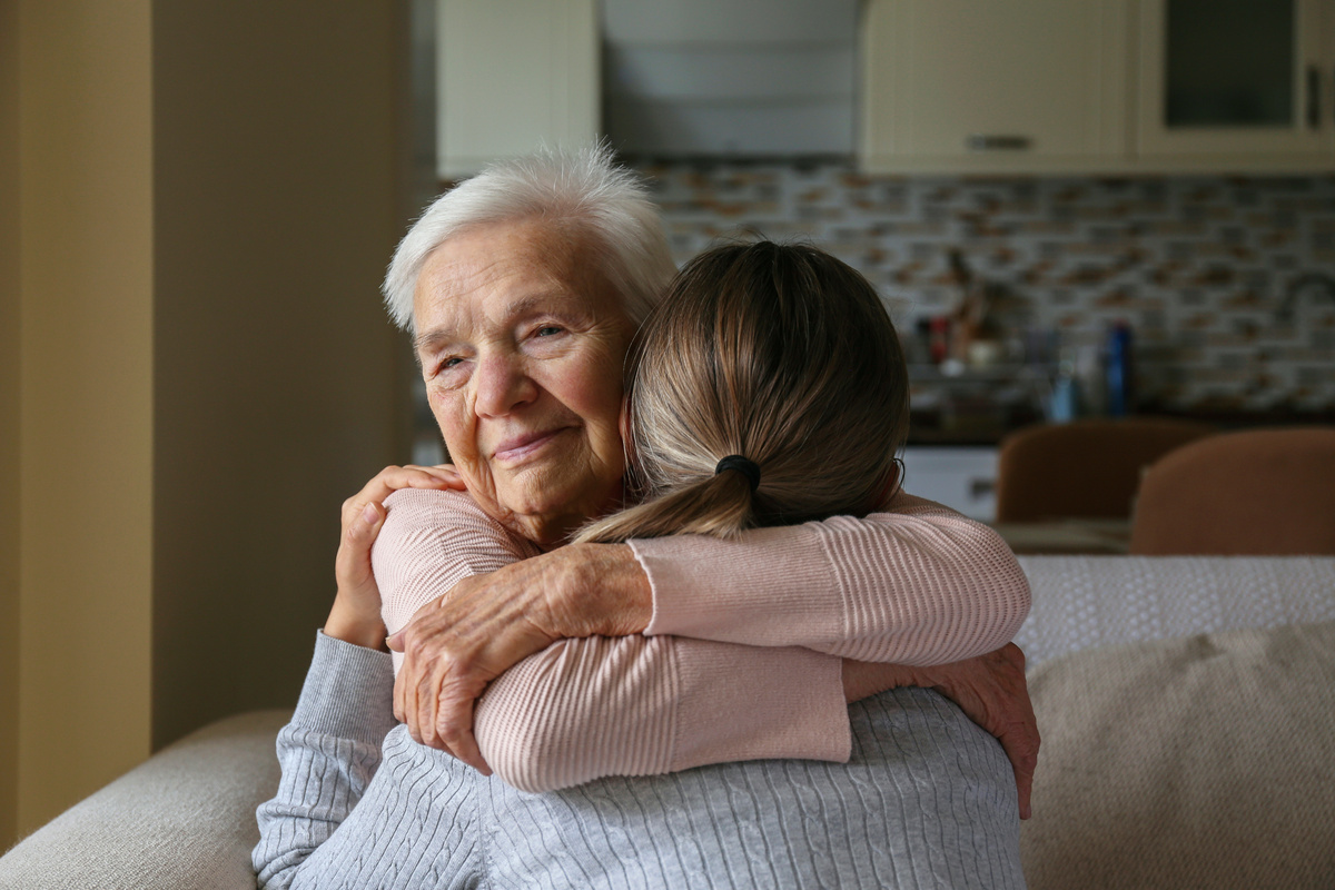 Grandmother and granddaughter hugging in the living room Two ad | Pension de reversion congé proche aidant