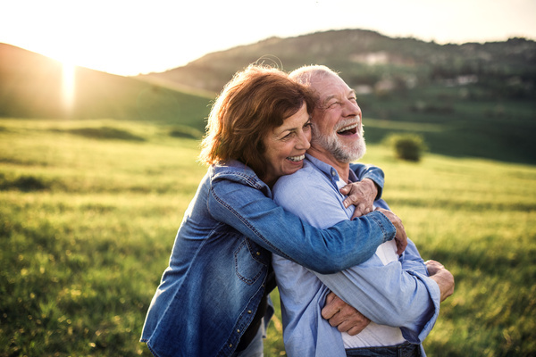 Side view of senior couple hugging outside in spring nature at sunset | Pension de reversion retraités aides de la caf