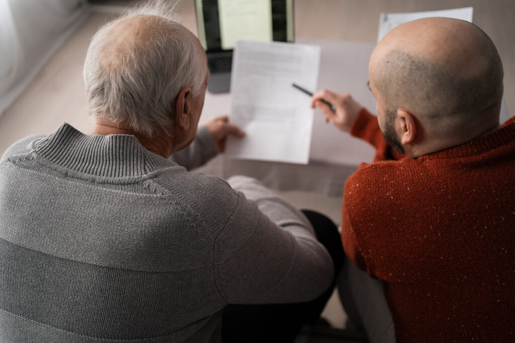 senior old man holding documents reading bills paying bank speak with his consultant payments taxes and family retirement finances | Pension de reversion impôts 2025