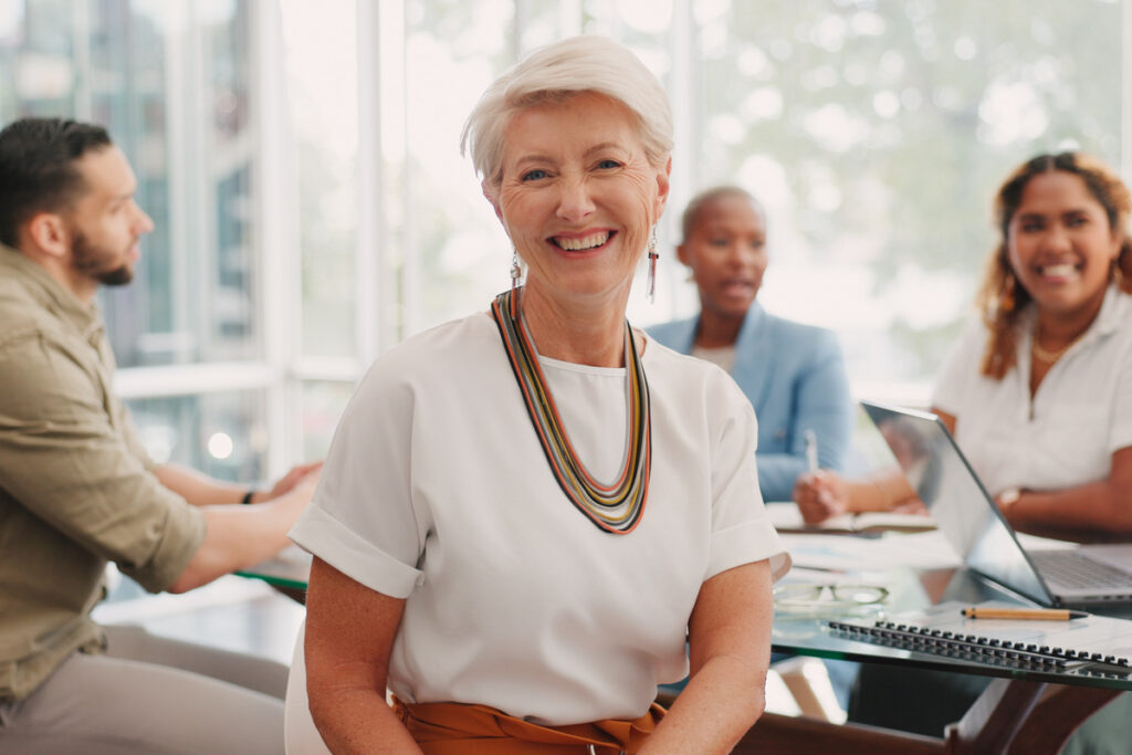 Elderly business woman management and smile for team meeting planning or corporate collaboration at office Portrait of senior CEO smiling for teamwork conference or creative startup at workplace | Pension de reversion emploi des seniors