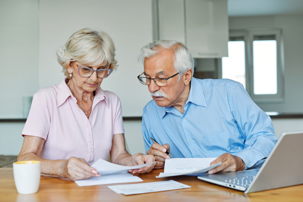 woman man senior bill finance retirement couple home document laptop wife computer budget elderly together mature old retired paperwork tax | Pension de reversion un couple remplissant le formule cerfa n°13710*04 et réunissant toutes les pièces à fournir pour leur demande du minimum vieillesse