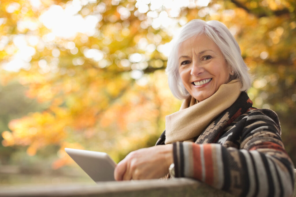 minimum_vieillesse-femme-souriante.jpg | Pension de reversion Femme senior souriante consultant des informations sur le Minimum Vieillesse (ASPA) en ligne sur sa tablette.