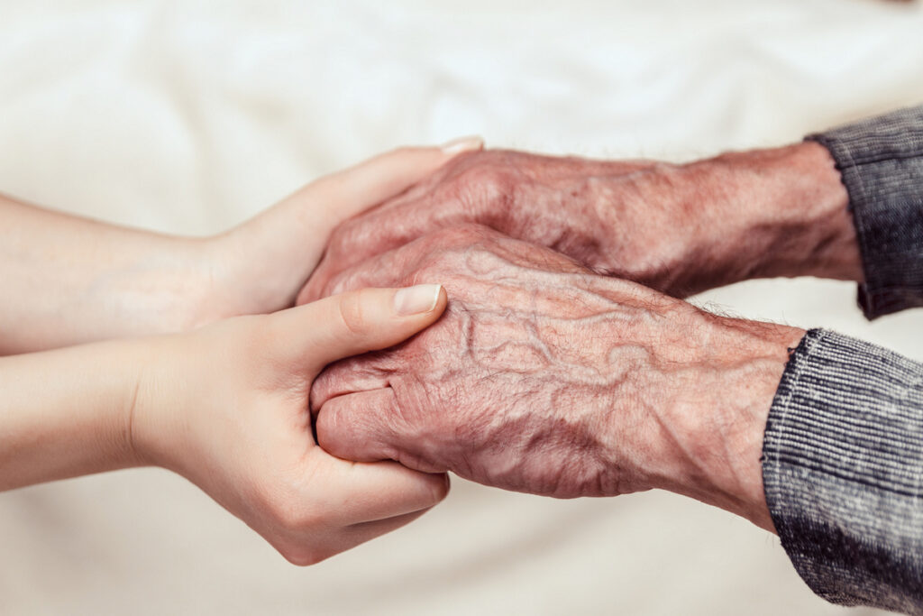 Hands of the old man and a young woman toning | Pension de reversion Mains serrées symbolisant le conseil pour optimiser les points Agirc-Arrco et la réversion.