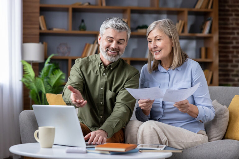 Un couple senior analyse ses droits au cumul réversion et retraite anticipée 2026 sur un ordinateur portable avec des documents officiels.