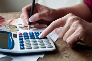 pension réversion 2026 montant net | Pension de reversion Femme calculant le montant net de sa pension de réversion 2026 avec une calculatrice et des documents administratifs.