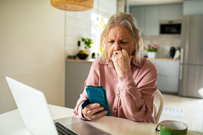 Retraitée inquiète devant son ordinateur et son smartphone après le bug informatique Agirc-Arrco.