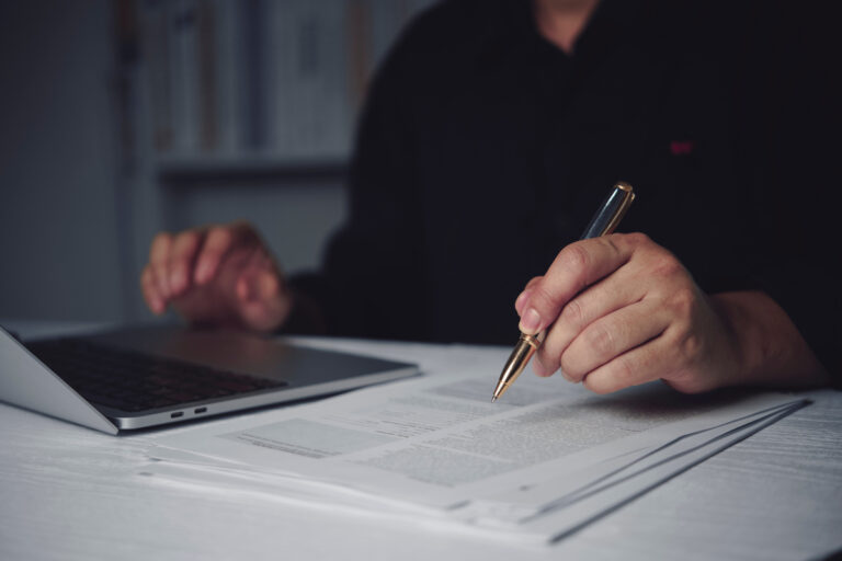 Personne remplissant des formulaires de pension de réversion après le décès d'un actif sur un bureau avec ordinateur.