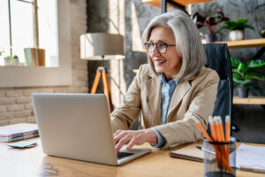Droit à l'erreur réversion : démarche en ligne | Pension de reversion Femme senior utilisant son ordinateur pour activer son droit à l'erreur réversion et corriger sa déclaration sans pénalités.