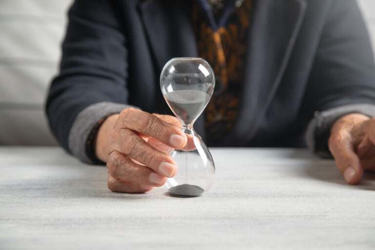 Personne senior tenant un sablier pour anticiper sa retraite malgré une carrière hachée