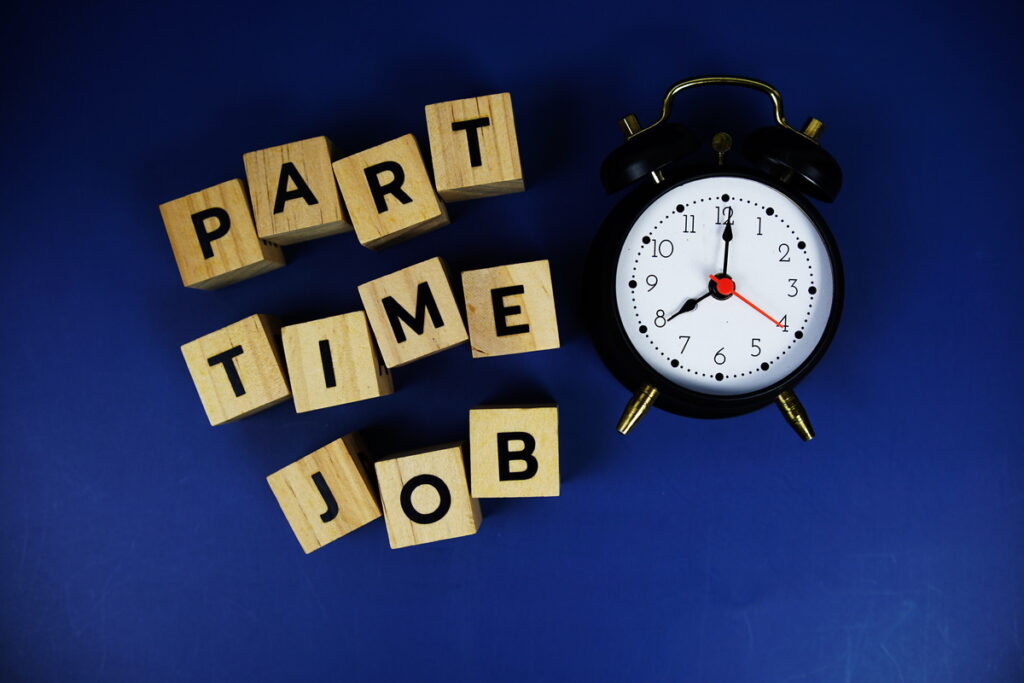 Part Time Job with wooden blocks alphabet letters and alarm clock on blue background | Pension de reversion Des cubes en bois formant l'inscription "Part Time Job" à côté d'un réveil sur fond bleu pour illustrer la retraite progressive.
