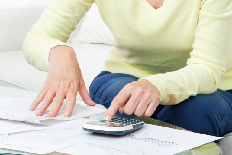 Une femme senior utilise une calculatrice pour simuler le cumul de plusieurs pensions de réversion.