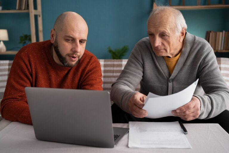 Un fils aide son père à remplir un dossier de pension de réversion sur ordinateur