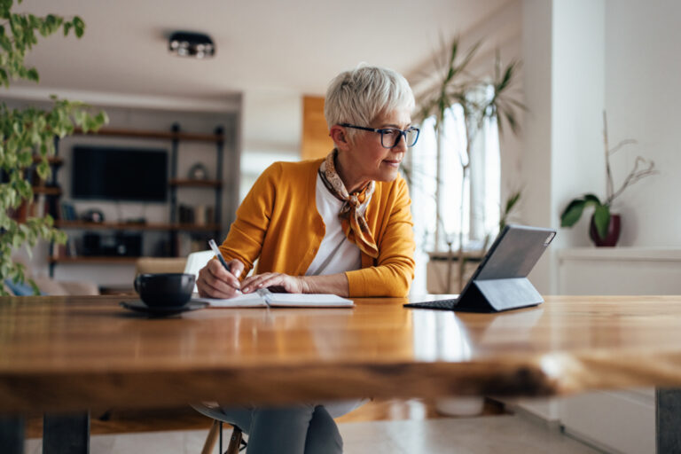 Une femme senior consulte sa tablette pour savoir comment saisir la Commission de Recours Amiable après une erreur de l'Assurance Retraite.