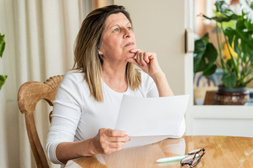Tout savoir sur le versement de votre 1ère réversion Agirc-Arrco | Pension de reversion emme âgée consultant ses documents administratifs pour sa 1ère réversion Agirc-Arrco