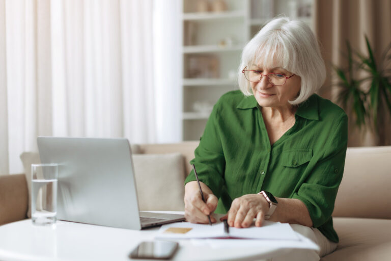 Femme senior gérant sa pension de réversion de la fonction publique sur ordinateur