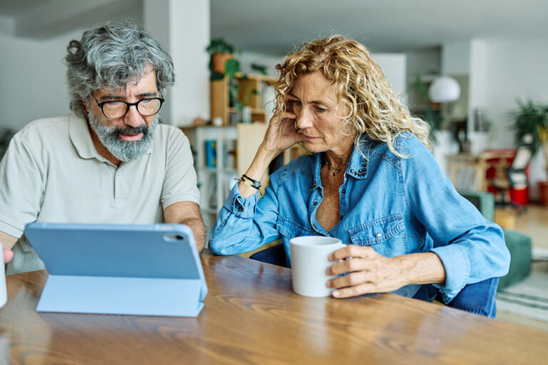 Couple vérifiant les impôts sur leur pension de réversion sur une tablette