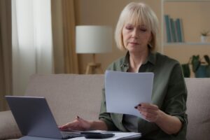 Gérer les démarches après un décès pendant l'instruction d'une retraite | Pension de reversion Femme lisant des documents administratifs après un décès pendant l'instruction de la retraite