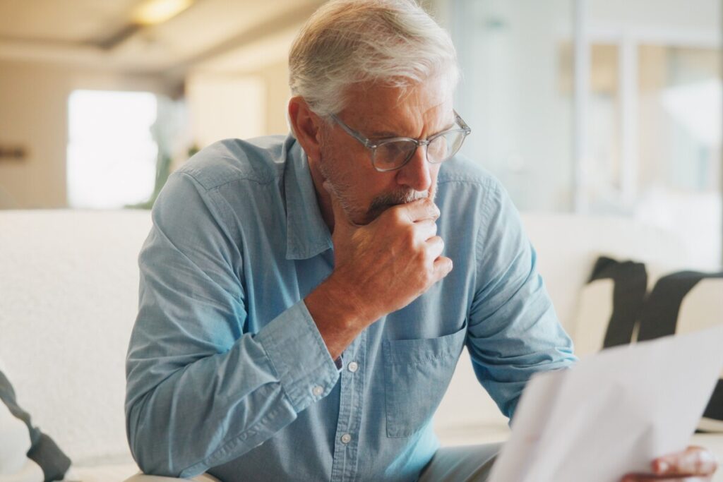 Dossier de réversion incomplet : homme lisant un courrier administratif | Pension de reversion Senior consultant inquiet face à un dossier de réversion incomplet et des documents administratifs bloqués