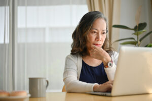 Femme senior concentrée sur son ordinateur effectuant une correction de carrière sur le site de l'Assurance retraite