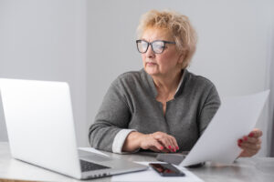 Femme senior active consultant ses documents pour le calcul de l'abattement sur les revenus d'activité et la pension de réversion