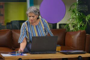 Femme senior consultant ses documents et son ordinateur pour calculer le plafond pension de réversion 2026.