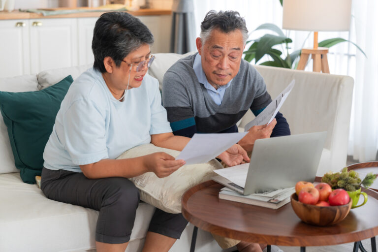 Couple de seniors analysant des documents et un ordinateur pour évaluer le coût d'un rachat de trimestres pour la réversion.