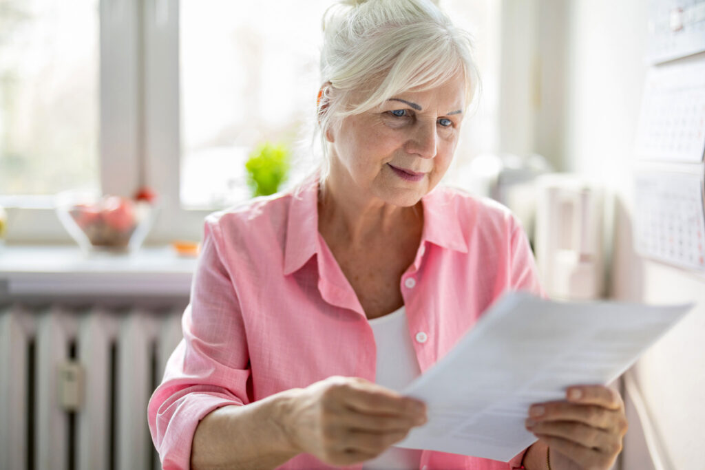 Femme senior consultant attentivement ses documents de ressources pour la pension de réversion