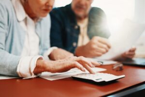Un couple vérifie des documents administratifs et utilise une calculatrice pour estimer ses trimestres validés pour la retraite.