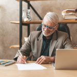 Homme d'âge mur rédigeant à son bureau une lettre de départ à la retraite
