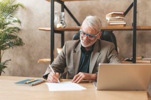 Homme d'âge mur rédigeant à son bureau une lettre de départ à la retraite